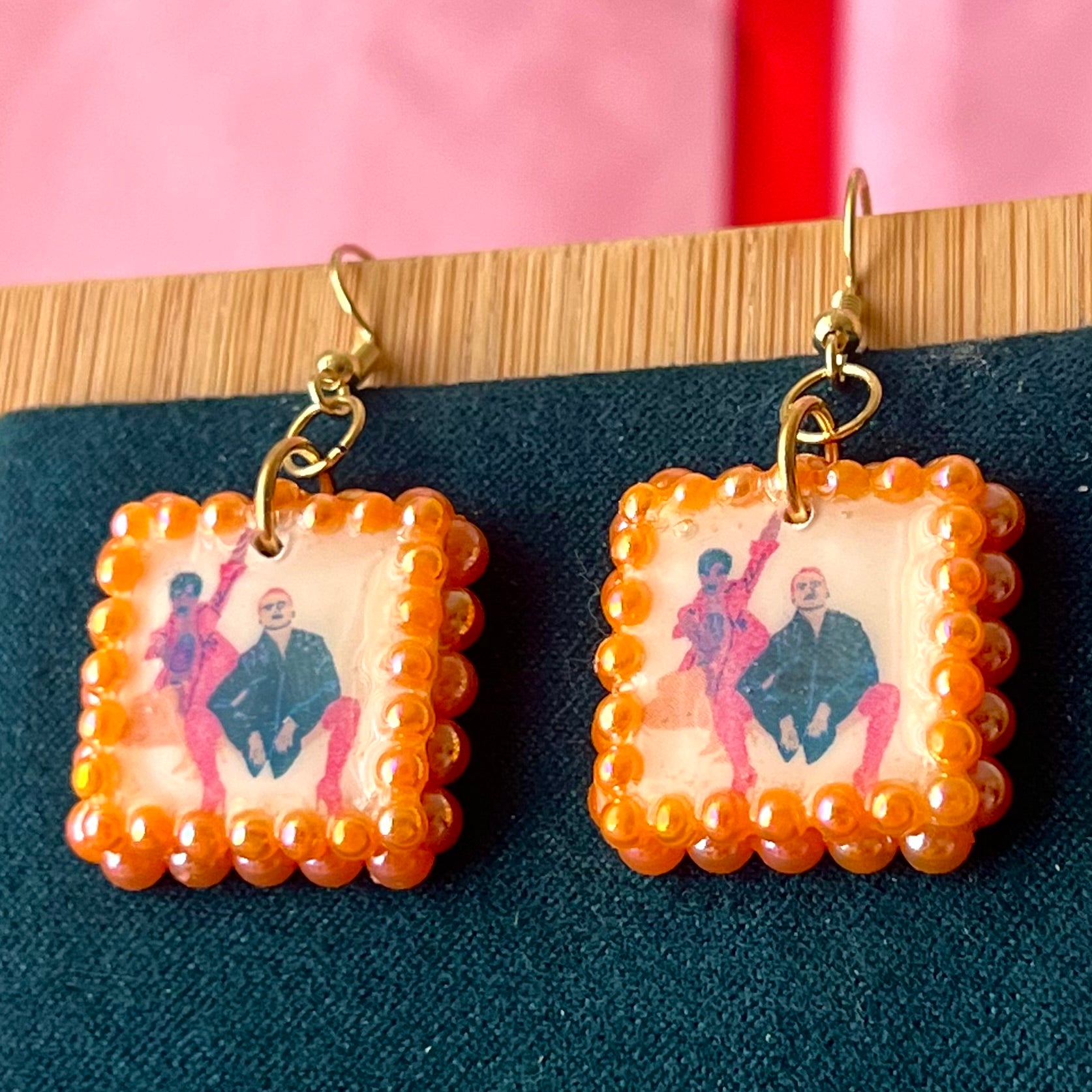 Handmade queer art earrings featuring polymer‑clay square charms with a “Strike a Pose” design, iridescent orange pearl drops, and 18k gold‑plated hypoallergenic findings – lightweight square charms, LGBTQ‑pride, statement piece, ready to ship in 1–3 days.