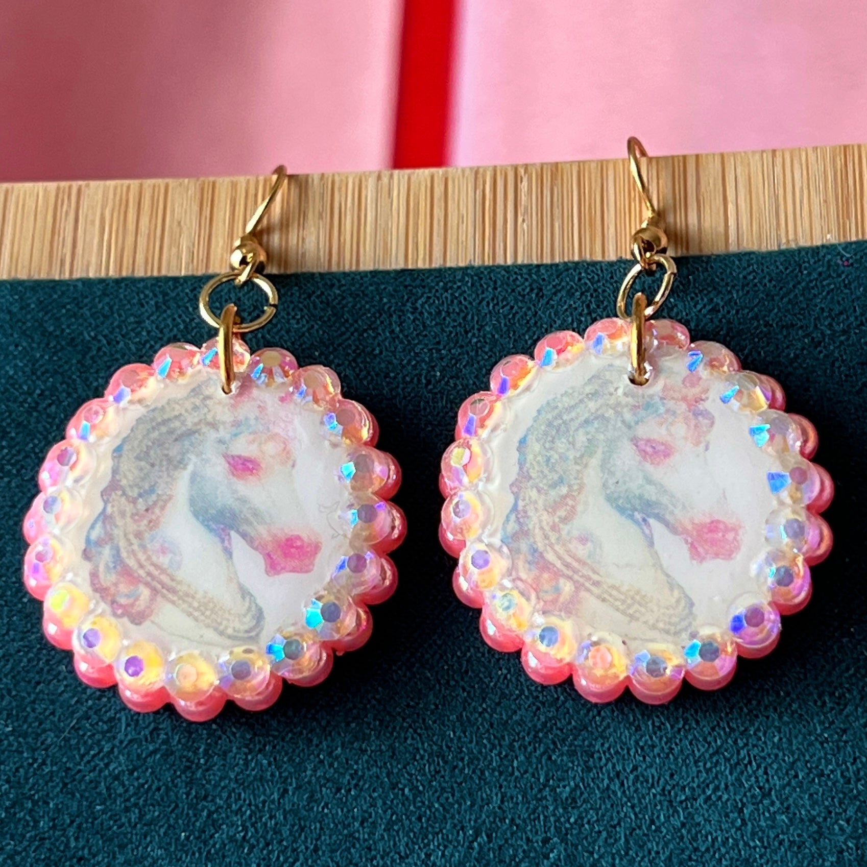 Alt text: "Handmade unicorn earrings featuring a pastel polymer‑clay charm with a soft fairy‑core unicorn, bedazzled by iridescent pink pearls and white gems, set in a gold‑plated fishhook finding; a whimsical, sparkly dangle earring perfect for Y2K, coquette, and pastel jewelry styles."