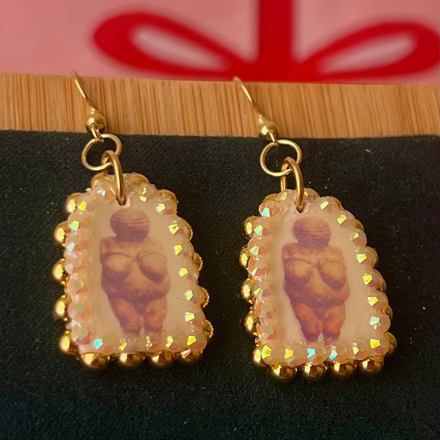 Handmade golden Venus of Willendorf portrait earrings featuring polymer‑clay image‑transfer arch charm (≈1 in), framed with metallic golden pearls and rhinestones, 18k gold‑plated hypoallergenic findings, museumcore/goddesscore art jewelry, gold statement earrings, wearable art, perfect gift for art lovers.