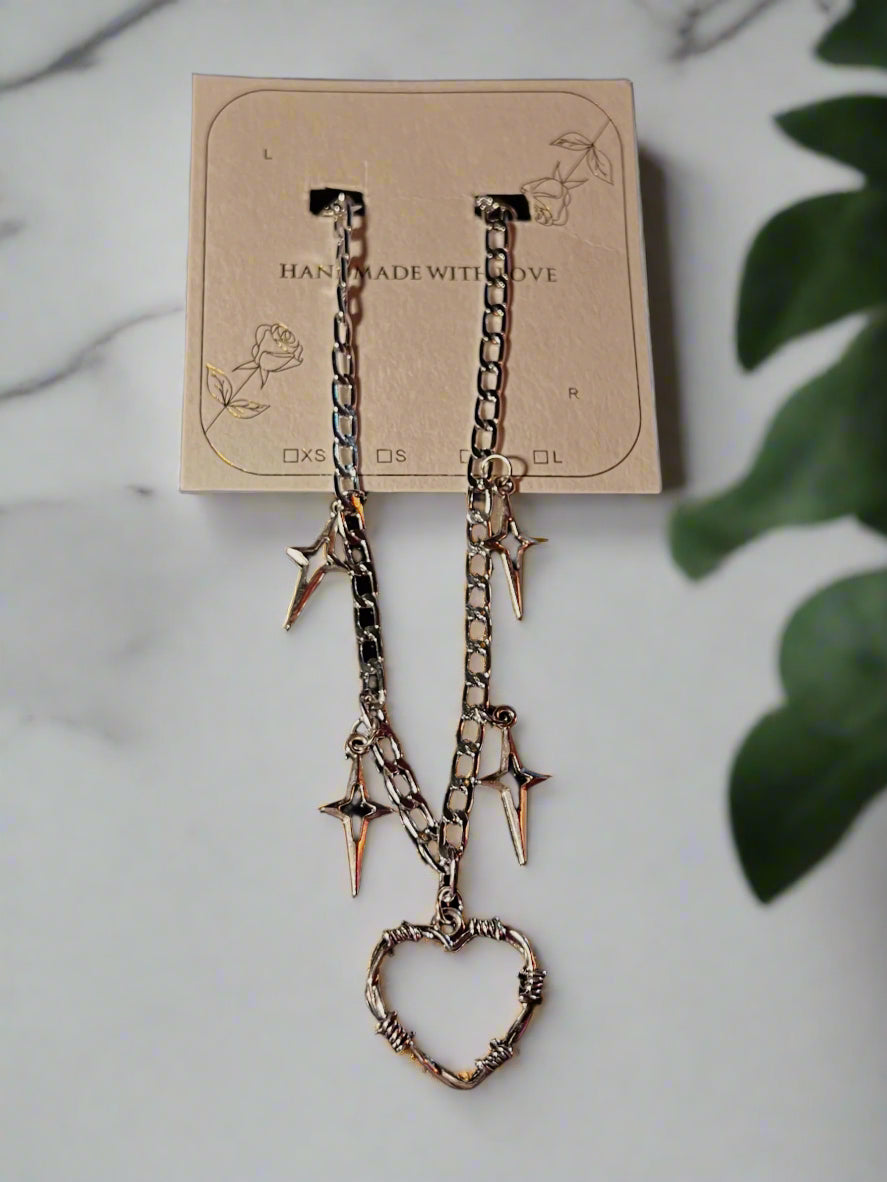 Pair of silver chain earrings with heart and spike charms on a display card.