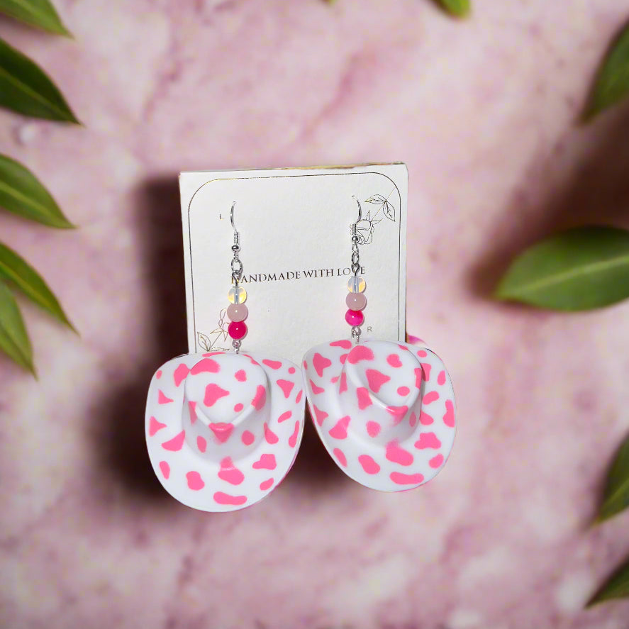 White earrings with pink heart patterns on a pink background