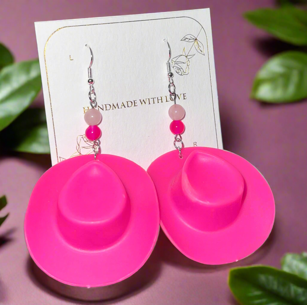 Pink earrings with beads on a card that says 'Handmade with Love' on a dark surface.