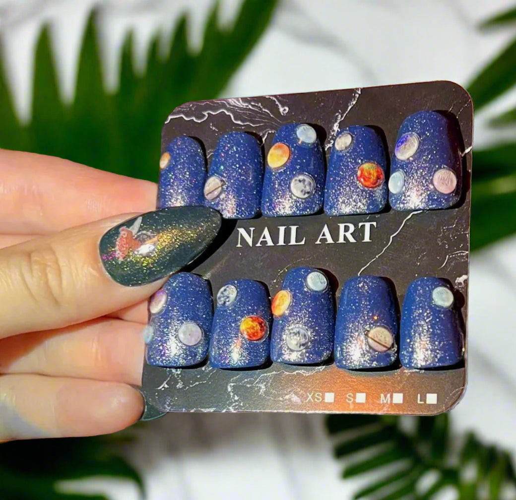 Nail art set with space-themed design on a cardboard holder