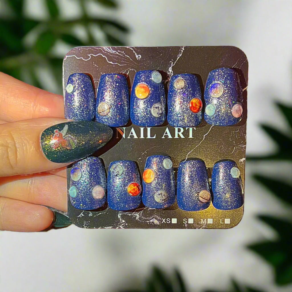 Set of blue glittery nail art with decorative elements on a display card.