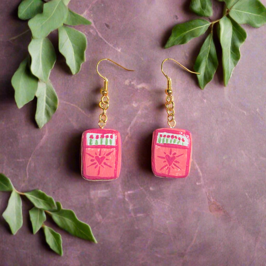 Pink earrings on a card with 'The Office Universe' branding against a dark background
