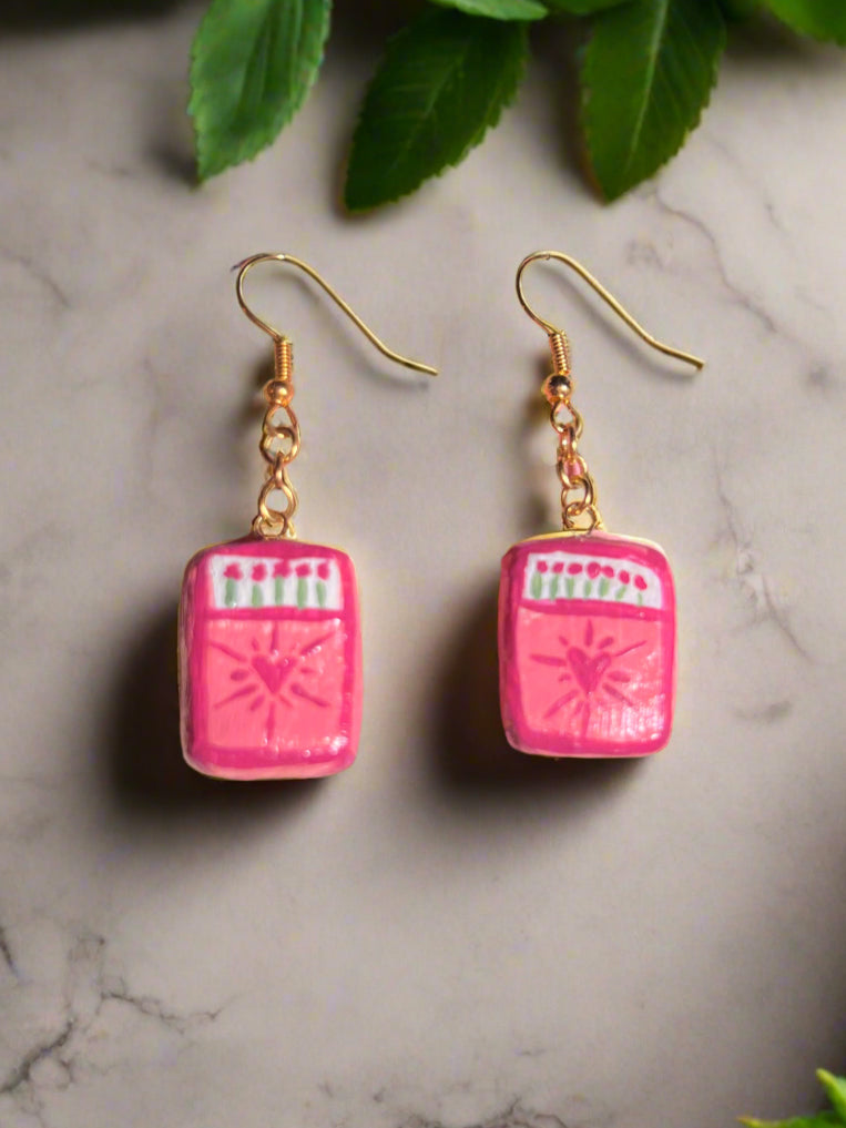 Pink earrings with gold hooks on a marble surface