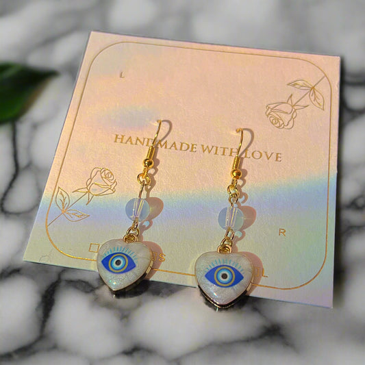 Heart-shaped earrings with eye design on a 'Handmade with Love' card.