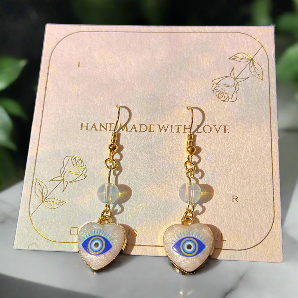Heart-shaped earrings with eye design on a 'Handmade with Love' card.
