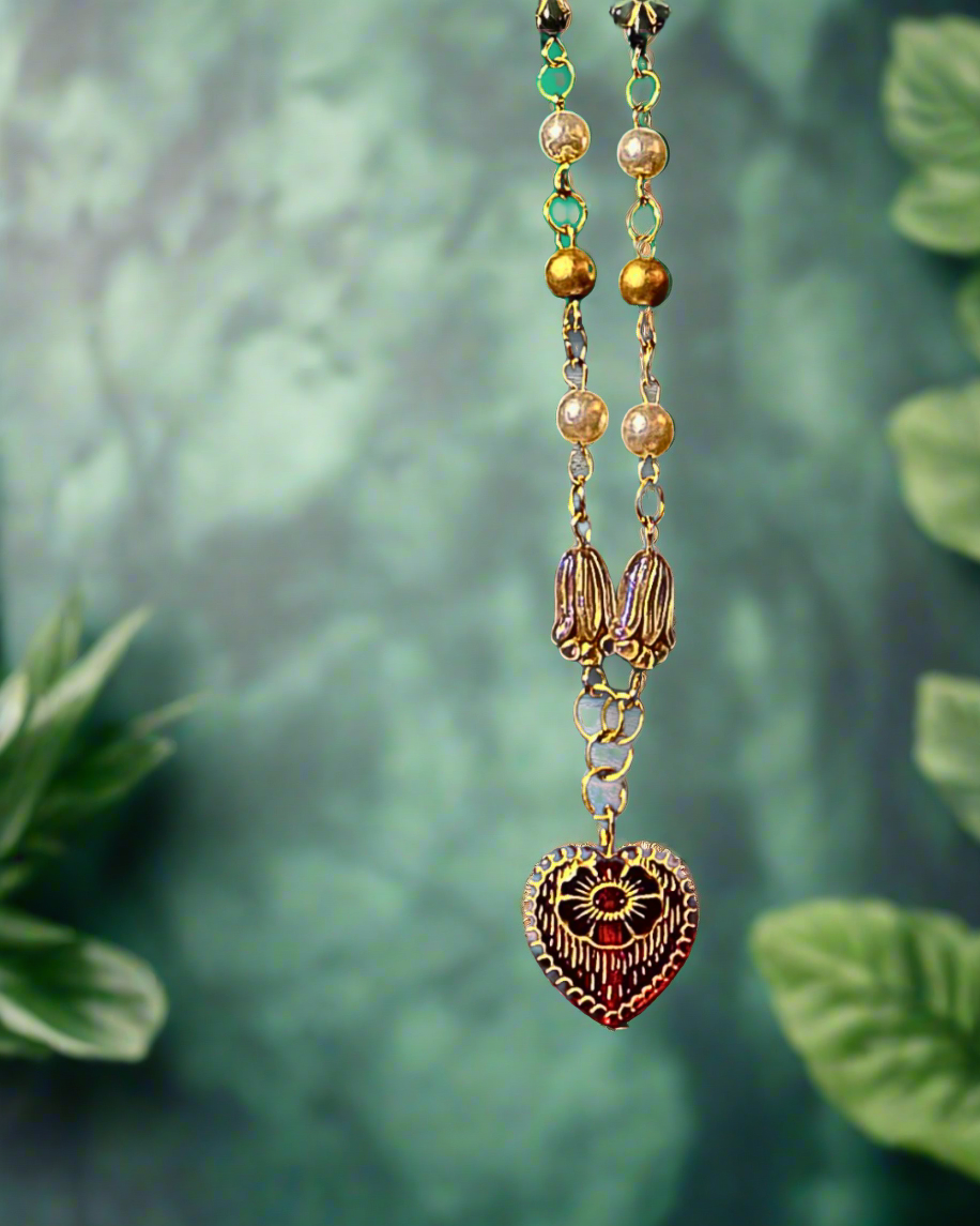 Pendant necklace with heart design on a beach setting, featuring 'Pirate Queen Of Hearts' and 'The Olive Universe'.