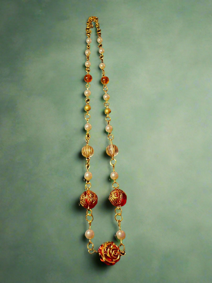 Necklace with gold, red, and white beads on a dark background