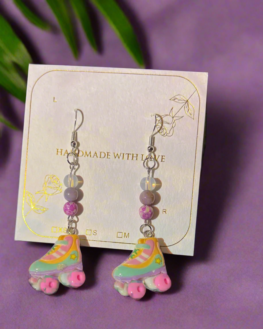 Pastel roller skate earrings on a purple background with a card that says 'Handmade with Love'.