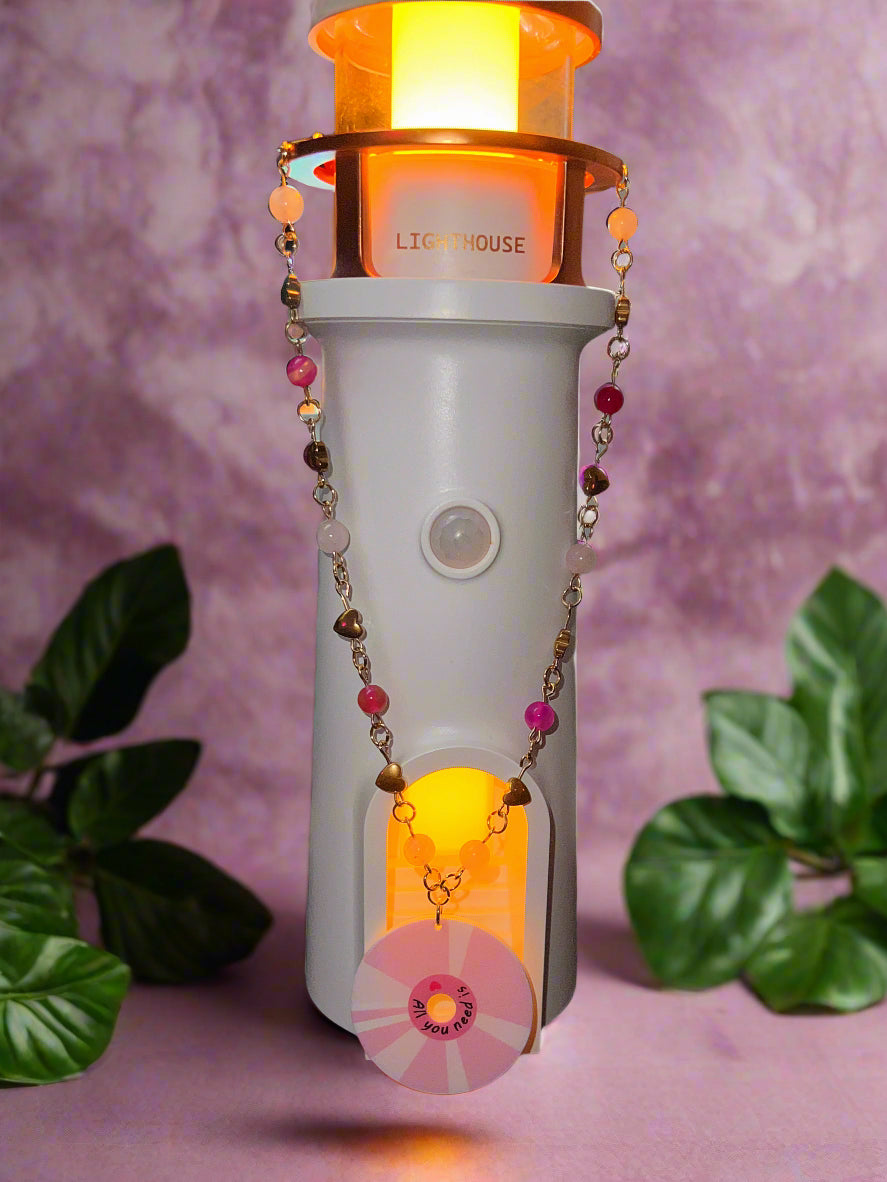 Lighthouse-shaped night light with decorative chain on a dark background
