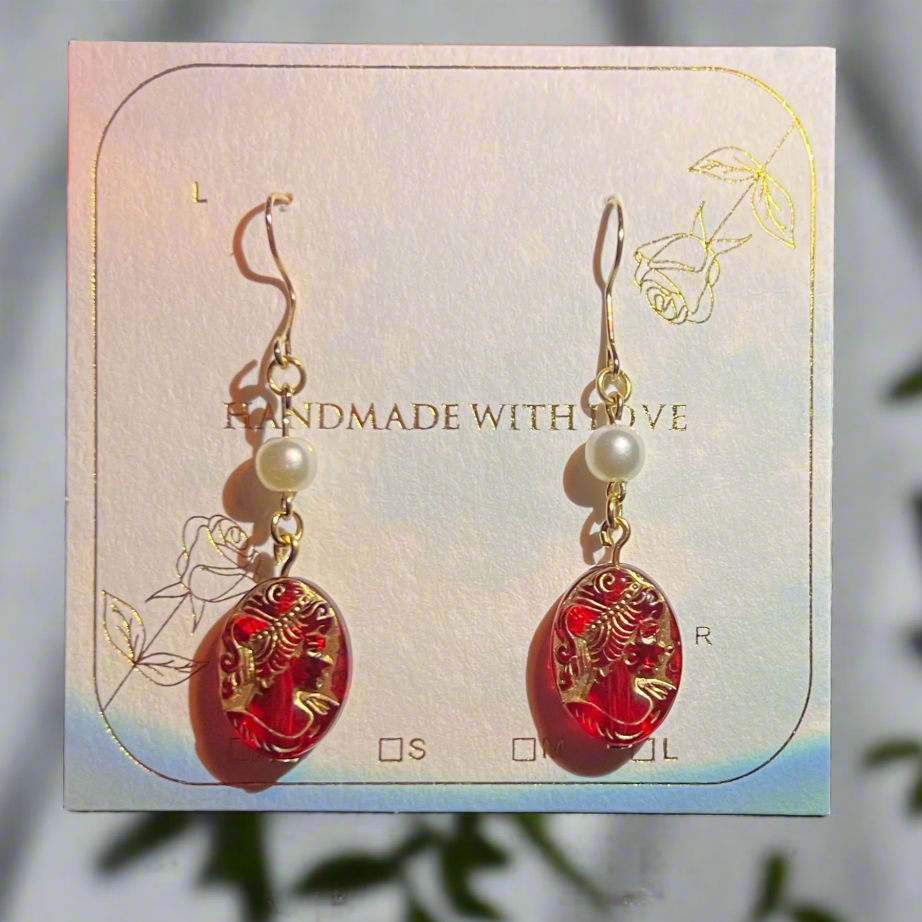 Pair of red earrings with gold accents and pearls on a 'Handmade with Love' card.