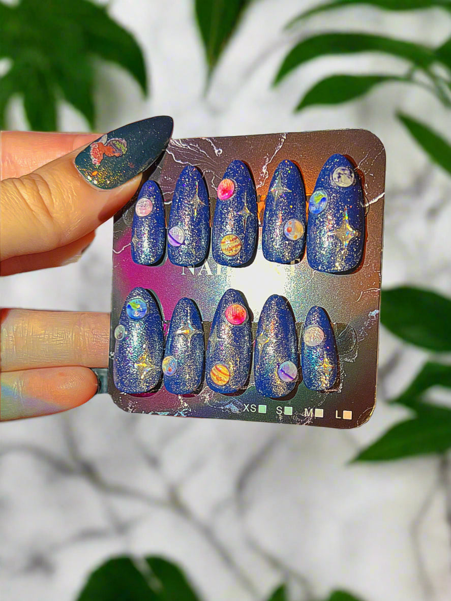 Set of blue nail art designs on a tray held by a hand with multicolored nail polish.