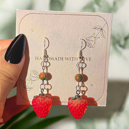 Strawberry-shaped earrings on a card with Unakite information overlay