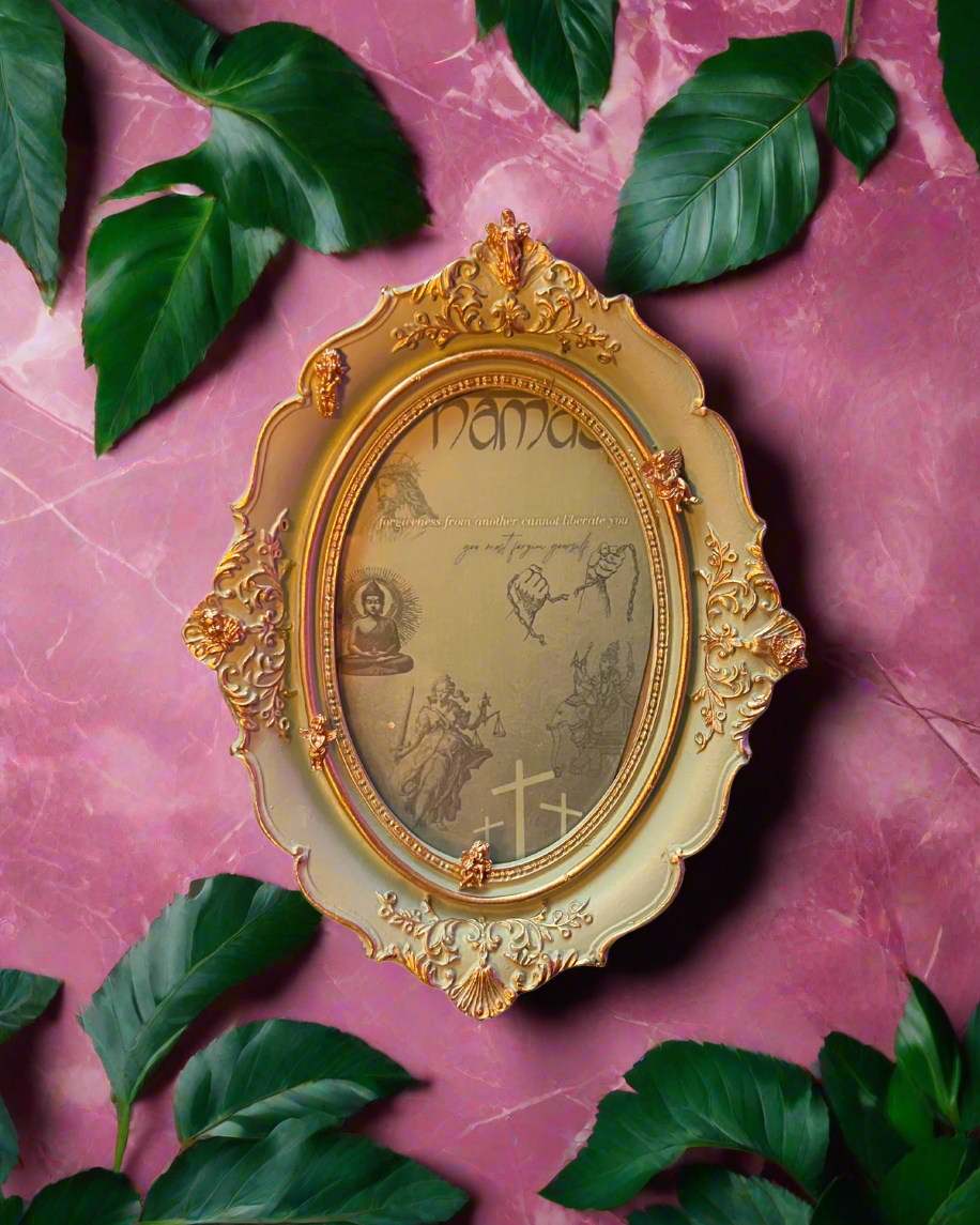Decorative gold frame with intricate designs on a pink marble background with green leaves.