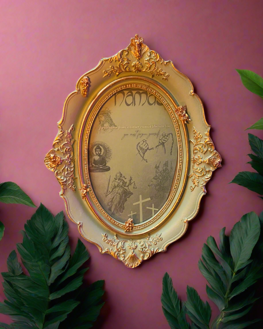 Decorative gold frame with intricate designs on a pink wall with green leaves.