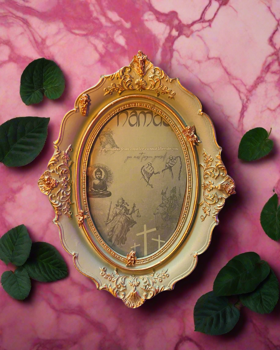 Decorative gold frame with intricate designs on a pink marble background with green leaves.