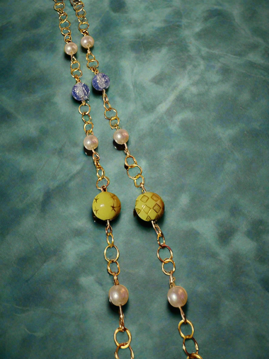 Necklace with gold chain, pearls, and beads on a black background