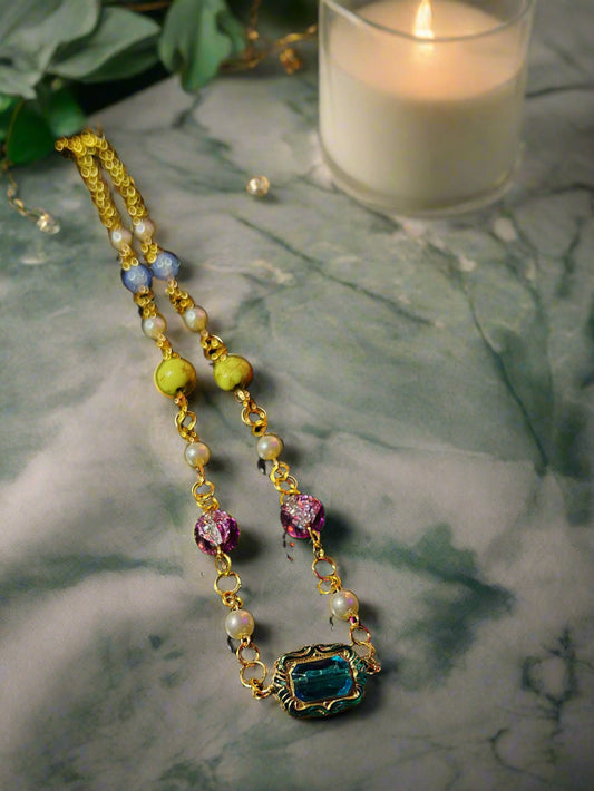 Necklace with colorful beads and a blue pendant on a dark surface