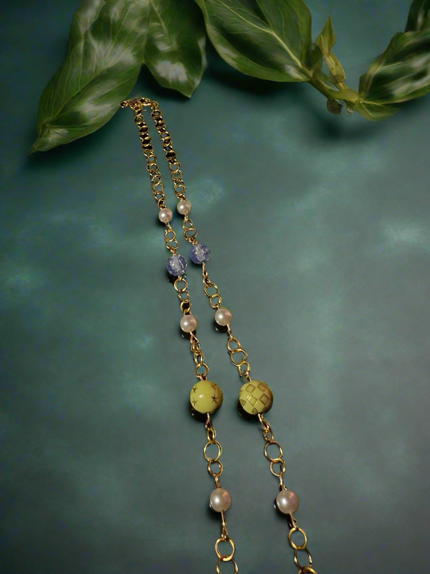 Two gold chains with beads on a dark background